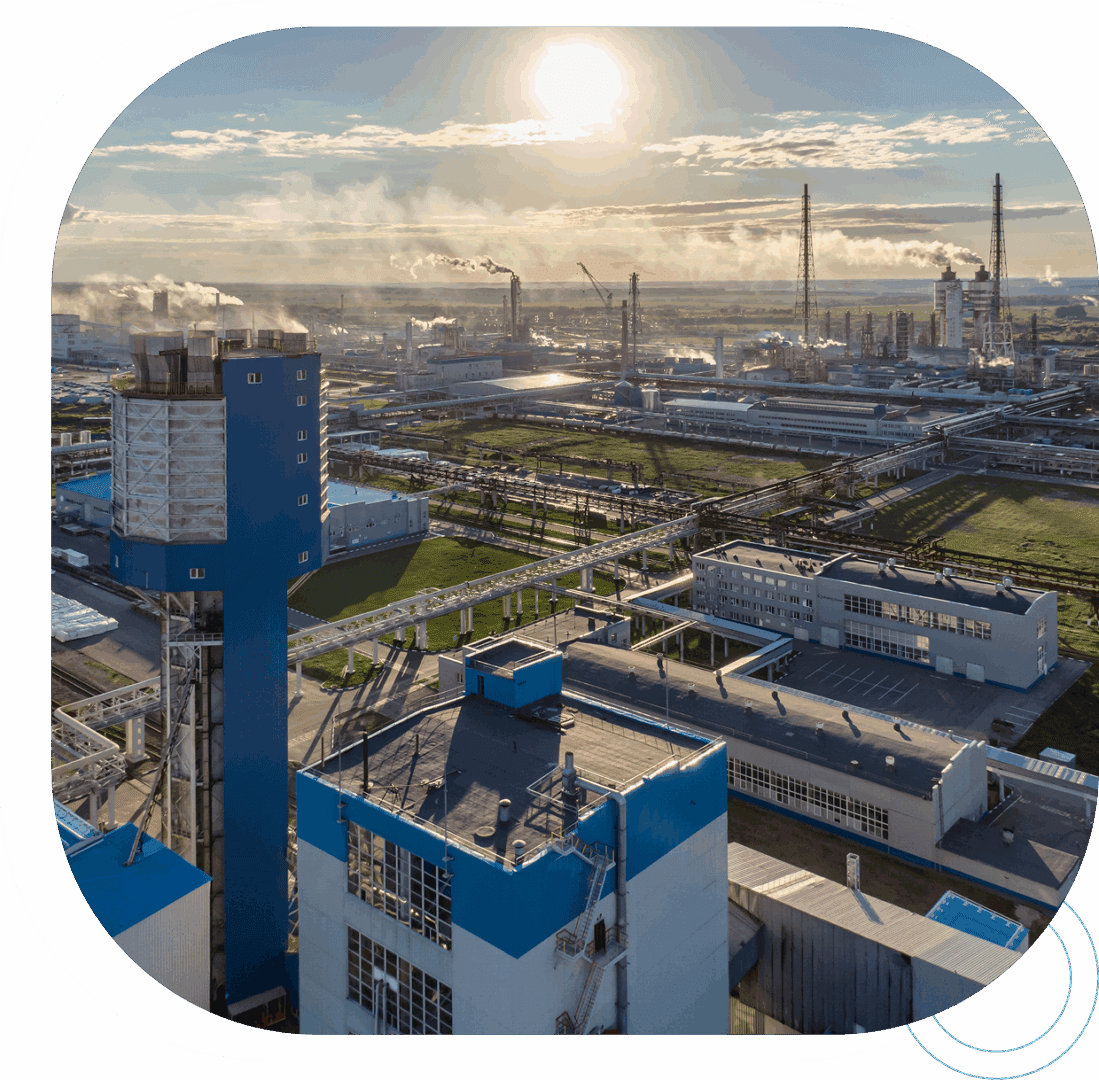 Industrial complex with smokestacks under bright sun.