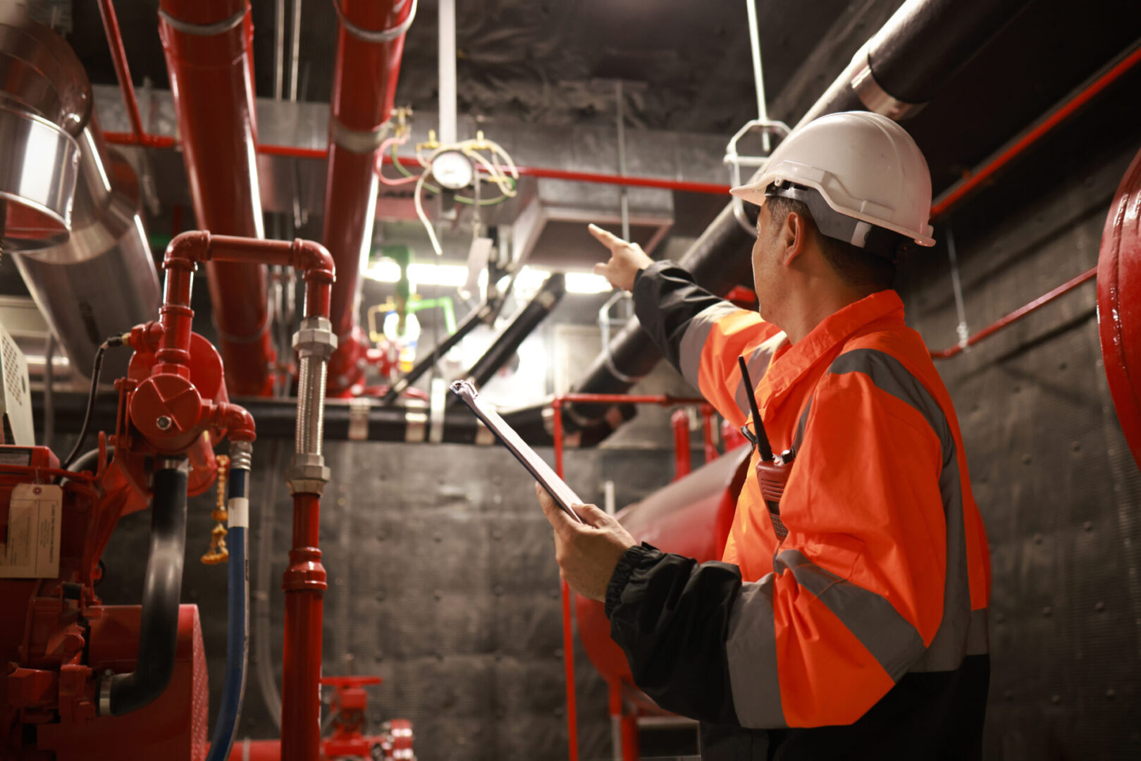 Engineer inspecting industrial pipes with clipboard.