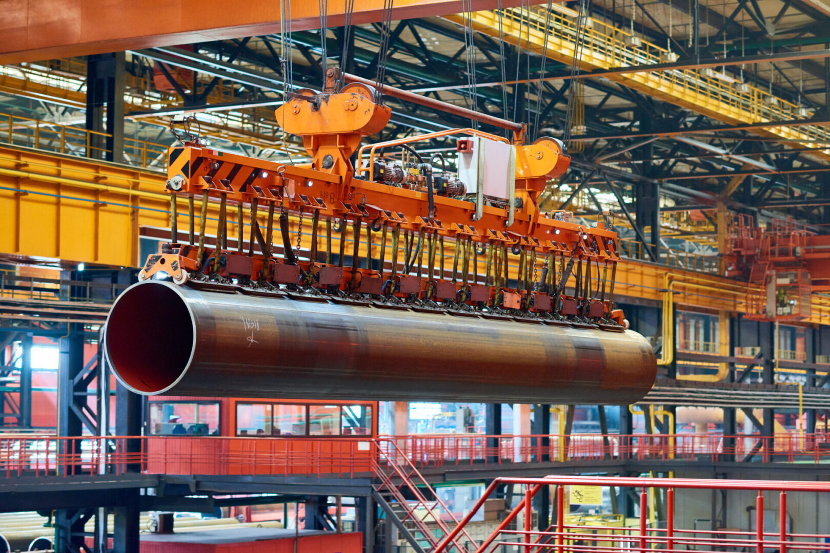 Powerful overhead crane moving with heavy tube alone factory shop